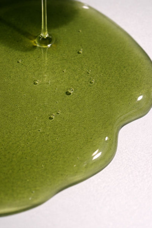 Close-up of green oil texture with droplets on a white background